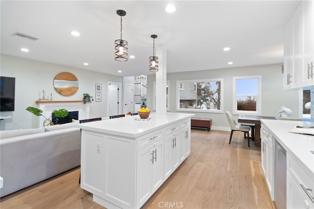 kitchen featuring open floor plan, light countertops, a fireplace, white cabinetry, and pendant lighting