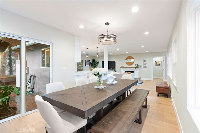 dining space with baseboards, a fireplace, light wood-style flooring, and recessed lighting