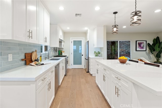 kitchen featuring stainless steel appliances, light countertops, hanging light fixtures, visible vents, and white cabinets