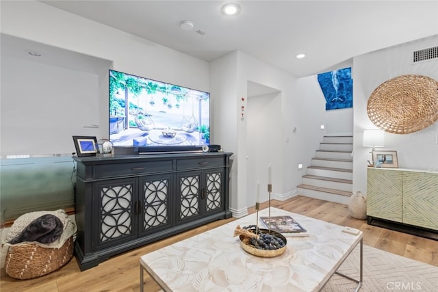 living area featuring recessed lighting, visible vents, wood finished floors, baseboards, and stairs