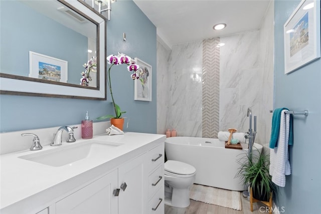 full bath with visible vents, toilet, wood finished floors, vanity, and a freestanding tub