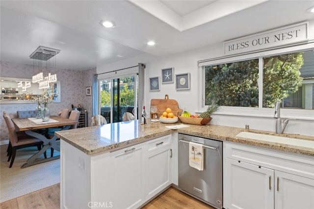 kitchen featuring wallpapered walls, light wood finished floors, white cabinets, stainless steel appliances, and a sink