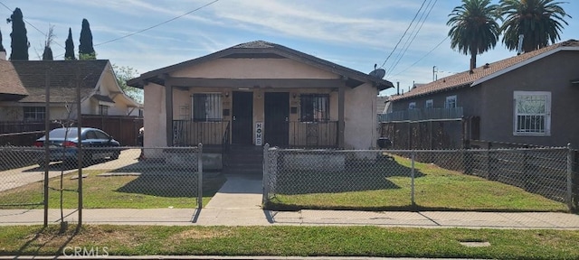 bungalow featuring a fenced front yard, a front yard, and stucco siding