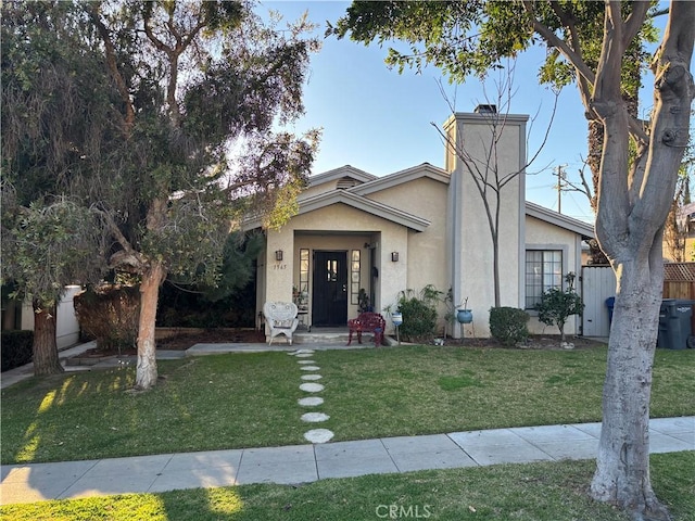 mid-century modern home with fence, a chimney, a front lawn, and stucco siding