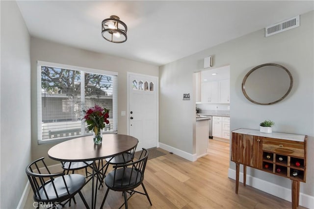 dining area with baseboards, visible vents, and light wood-style floors