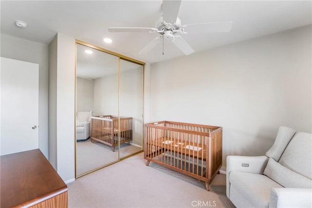 bedroom with ceiling fan, recessed lighting, a closet, a nursery area, and carpet