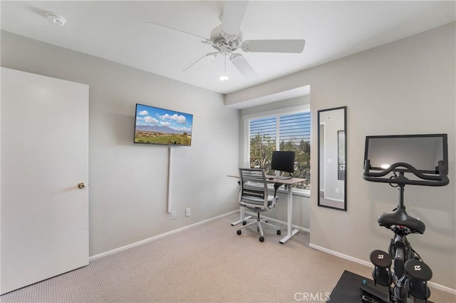 carpeted office space featuring ceiling fan and baseboards