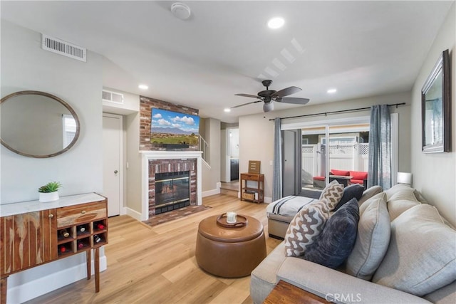 living room with recessed lighting, a fireplace, visible vents, and light wood-style floors