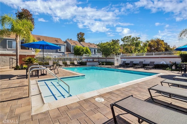 community pool with a patio area and fence