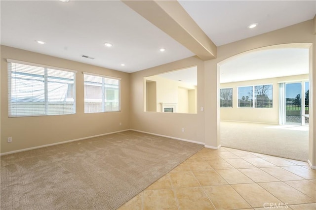 unfurnished room with visible vents, a wealth of natural light, and light colored carpet