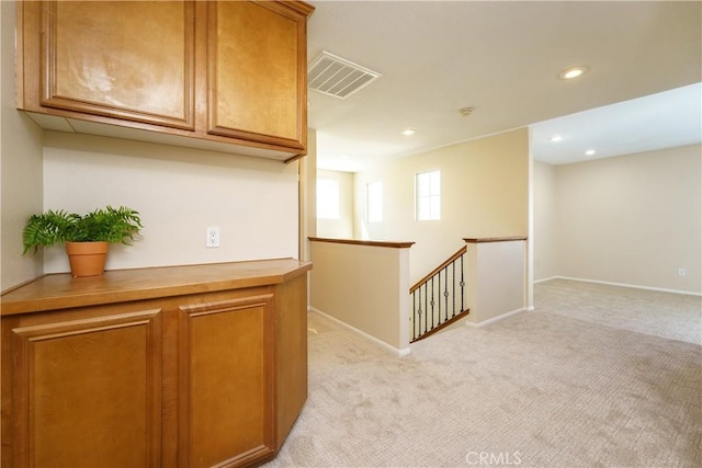 hall featuring recessed lighting, visible vents, light carpet, and an upstairs landing