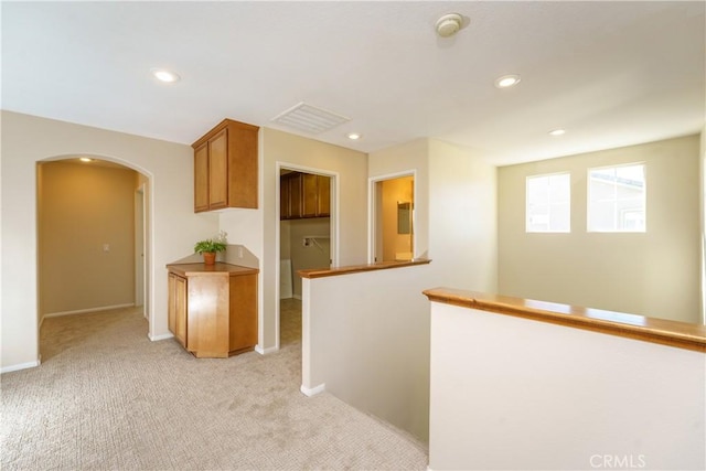 kitchen featuring recessed lighting, arched walkways, baseboards, and light colored carpet