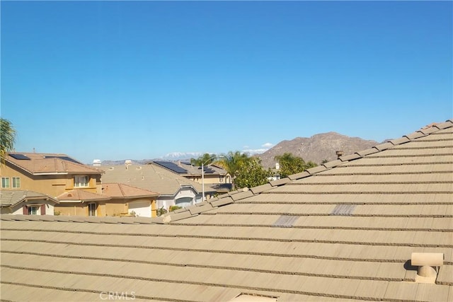 exterior details with a residential view, a tile roof, and a mountain view