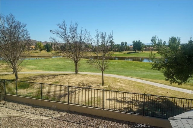 view of community featuring a lawn, a water view, and fence