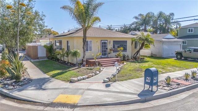 single story home featuring roof mounted solar panels, fence, a front lawn, and stucco siding