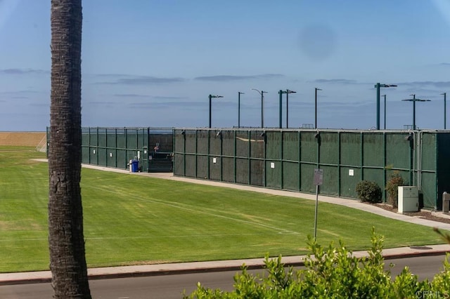 view of property's community featuring a yard, fence, and a tennis court