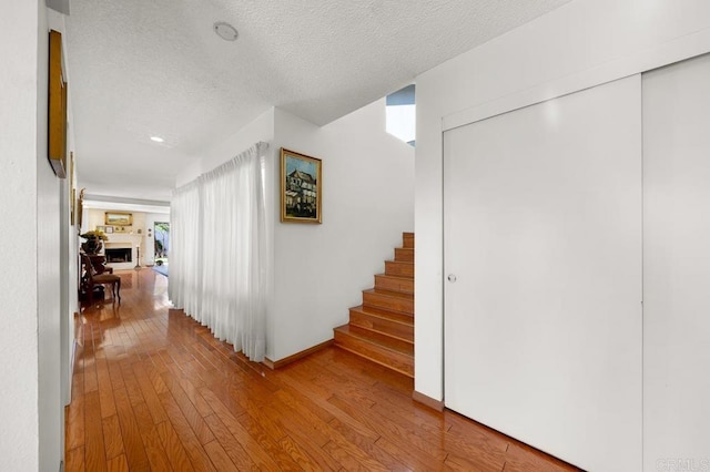 hallway with a textured ceiling, stairway, and wood finished floors