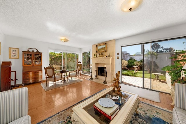 living room with a fireplace with flush hearth, a textured ceiling, and wood finished floors