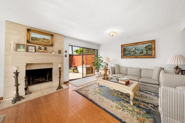 living area with a textured ceiling, a fireplace, and wood finished floors