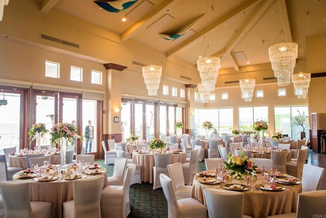 dining space featuring visible vents, a towering ceiling, beam ceiling, a healthy amount of sunlight, and a notable chandelier