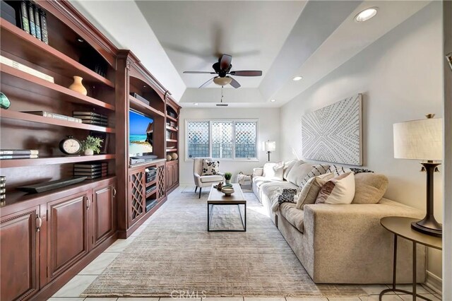 living area with recessed lighting, ceiling fan, a tray ceiling, and light tile patterned flooring