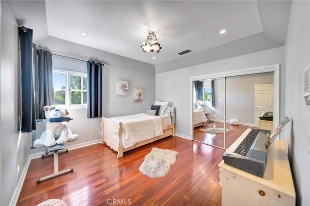 bedroom featuring baseboards, a closet, hardwood / wood-style flooring, and visible vents