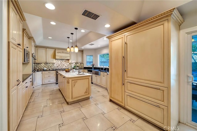 kitchen with visible vents, cream cabinets, a tray ceiling, pendant lighting, and backsplash