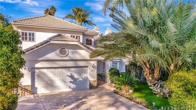 view of front of house featuring a garage, decorative driveway, a tile roof, and stucco siding