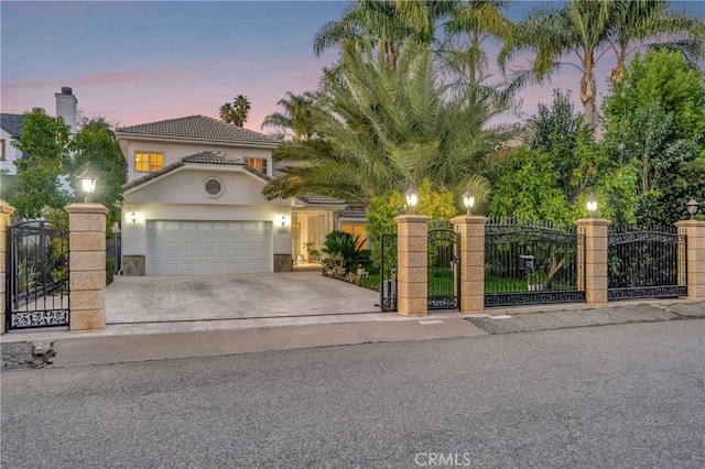 mediterranean / spanish home featuring a gate, fence, driveway, and an attached garage