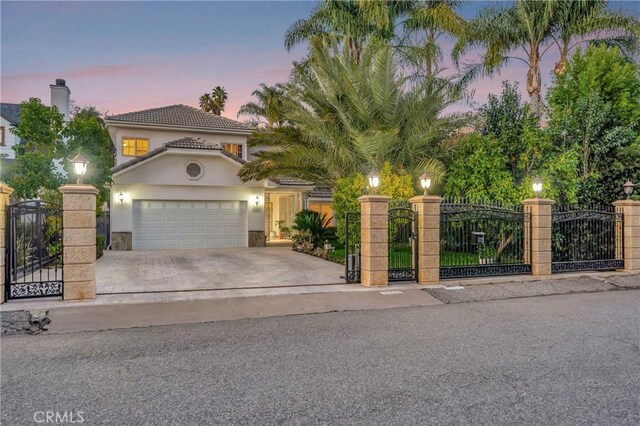 mediterranean / spanish home featuring a gate, a fenced front yard, concrete driveway, and stucco siding