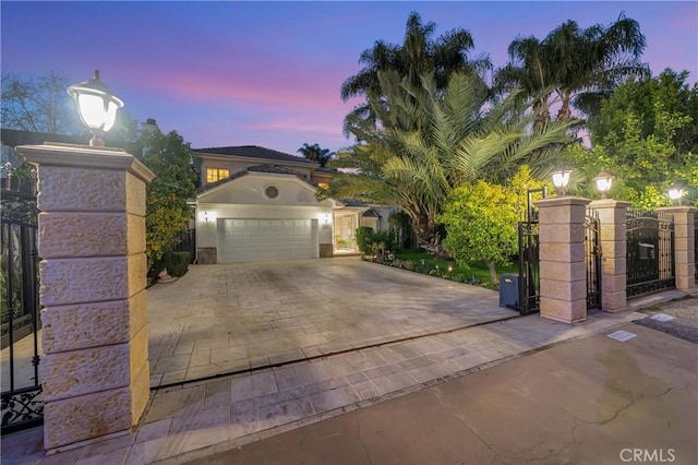 view of front of house with an attached garage, a gate, and decorative driveway