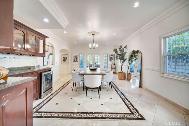 dining area with crown molding, arched walkways, baseboards, indoor wet bar, and wine cooler