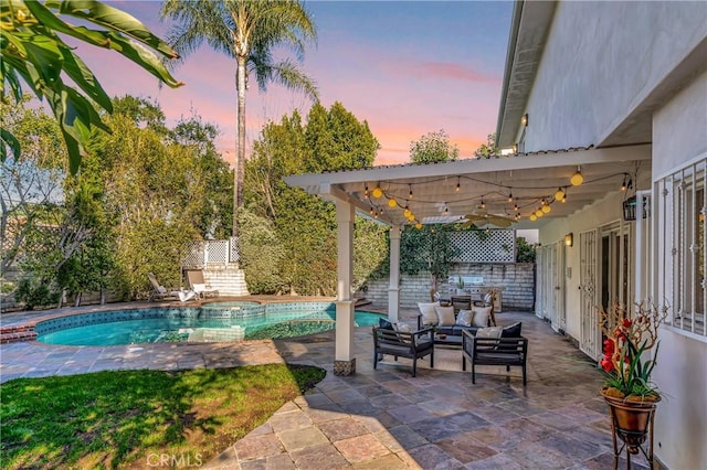 patio terrace at dusk featuring a pool with connected hot tub, a fenced backyard, and an outdoor hangout area