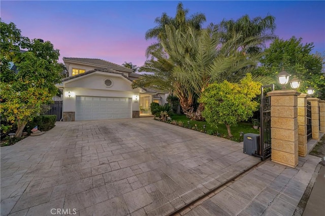 view of front of home featuring decorative driveway, an attached garage, fence, and stucco siding