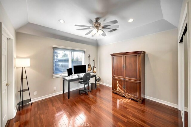 home office featuring dark wood finished floors, a ceiling fan, baseboards, a tray ceiling, and visible vents