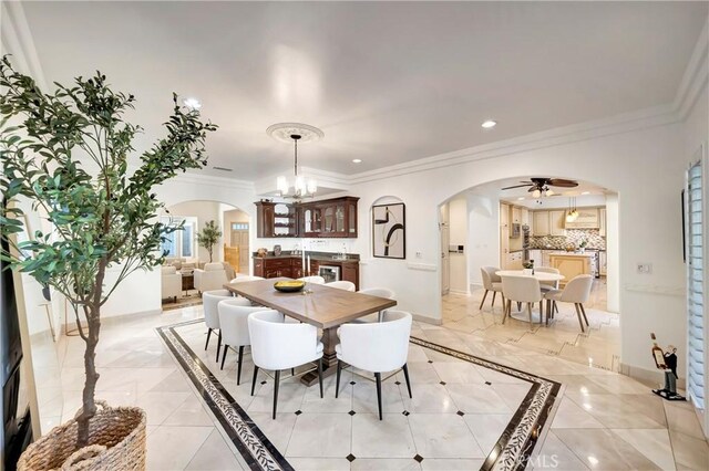dining area featuring crown molding, arched walkways, ceiling fan with notable chandelier, and recessed lighting