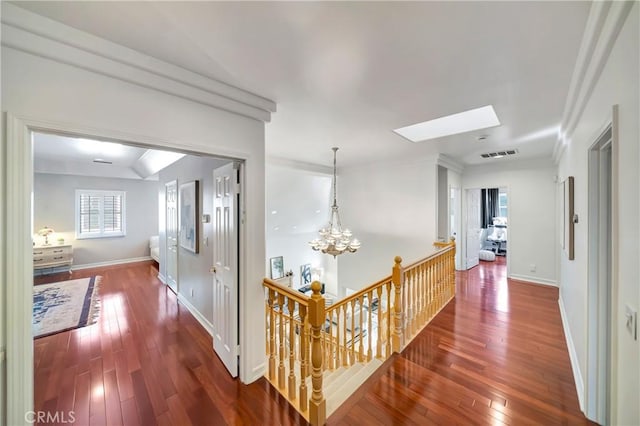 corridor featuring a skylight, a notable chandelier, visible vents, an upstairs landing, and hardwood / wood-style flooring