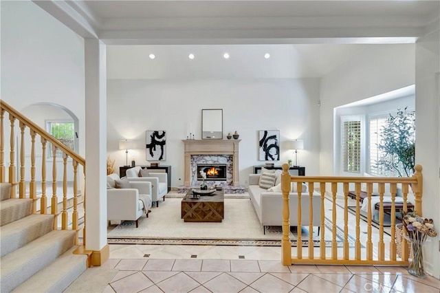 tiled living area with recessed lighting, a healthy amount of sunlight, a high ceiling, and a premium fireplace