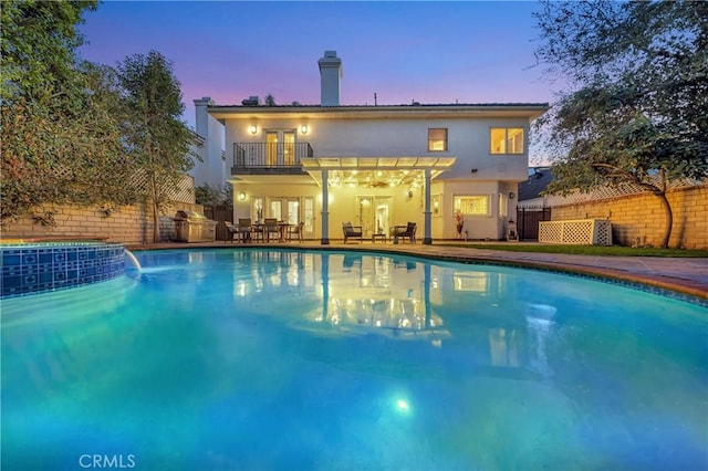 pool at dusk with a fenced in pool, fence, and a patio