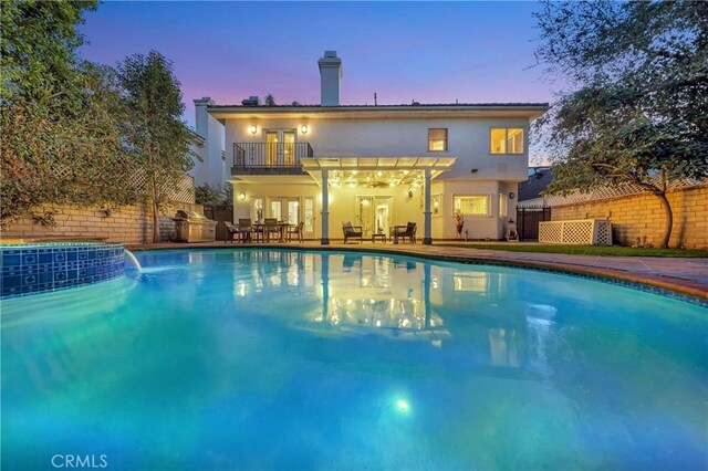 pool at dusk featuring a patio, fence, french doors, and a fenced in pool