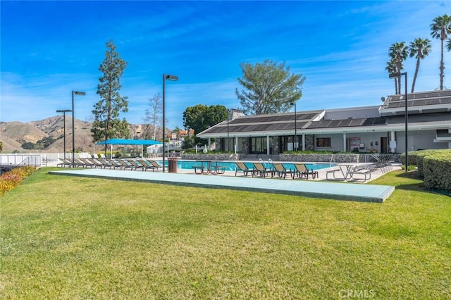 community pool with fence, a mountain view, and a yard