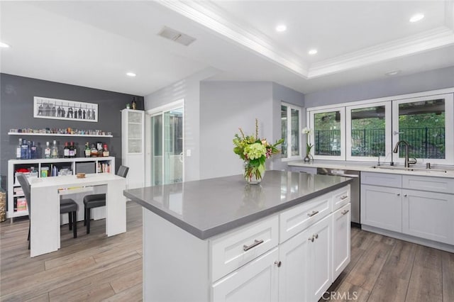 kitchen featuring visible vents, white cabinets, a center island, dark countertops, and a raised ceiling