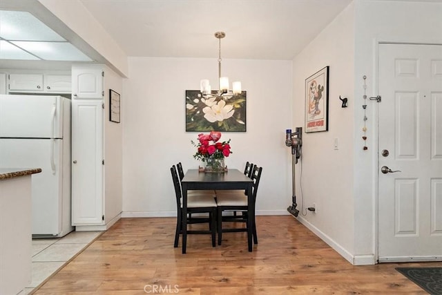 dining room featuring light wood-style floors, baseboards, and a chandelier