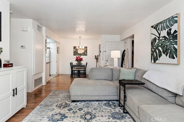 living area with a chandelier, visible vents, and wood finished floors