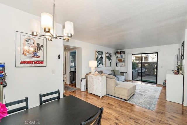 dining area with a notable chandelier, built in shelves, and wood finished floors