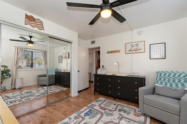 living area featuring baseboards, wood finished floors, visible vents, and a ceiling fan