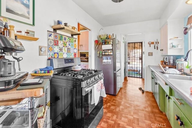 kitchen with open shelves, stainless steel appliances, light countertops, green cabinets, and a sink