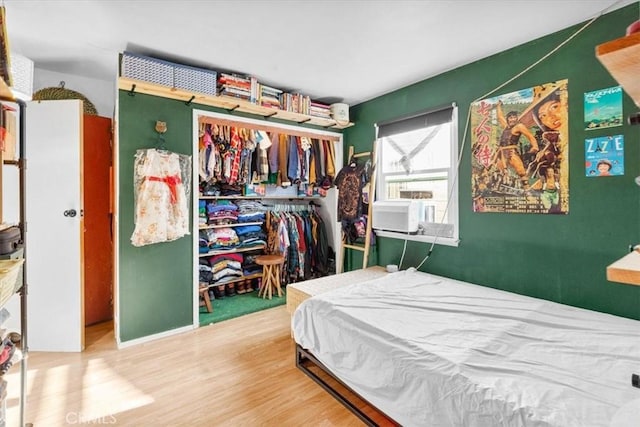 bedroom with cooling unit, a closet, and wood finished floors