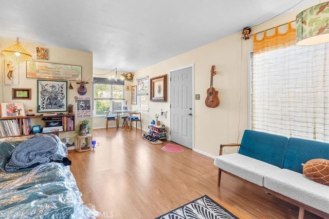 living area featuring baseboards, a chandelier, and wood finished floors