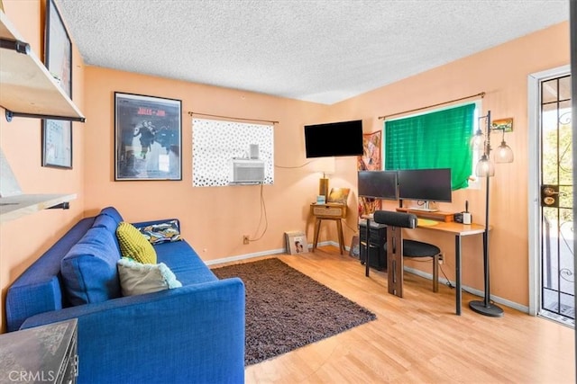 living area with baseboards, light wood-style flooring, and a textured ceiling